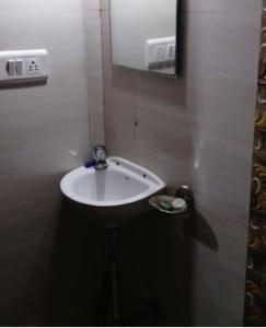 a white sink in a bathroom with a mirror at New Asian Dormitory in Mumbai