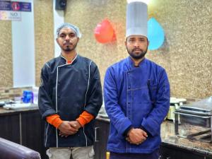Dois homens numa cozinha com um chapéu de chef. em Hotel Taj Palace near Mall Road em Shimla