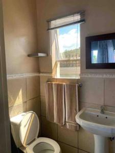 a bathroom with a toilet and a sink and a window at Flat in Rustenburg in Rustenburg