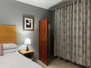 a bedroom with a bed and a door and a lamp at Flat in Rustenburg in Rustenburg