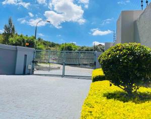 a bush in front of a fence with a building at Flat in Rustenburg in Rustenburg