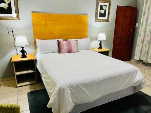 a bedroom with a large white bed with two lamps at Flat in Rustenburg in Rustenburg