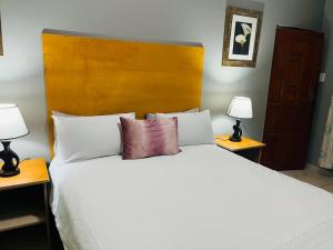 a bedroom with a large white bed with two lamps at Flat in Rustenburg in Rustenburg +3 photos