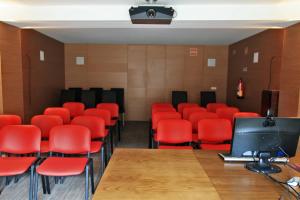 uma sala de conferncias com cadeiras vermelhas e uma televiso em Casa Dos Poos em Vilar Torpim mais 30 fotografias