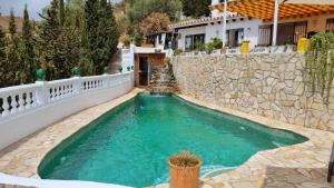 a swimming pool in a yard with a stone wall at La buena vida. in Málaga