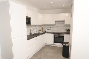 - une cuisine blanche avec des placards blancs et un évier dans l'établissement Central Watford Apartment, à Watford