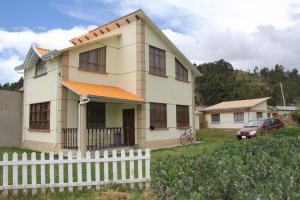 dom z białym płotem przed nim w obiekcie Lago Sagrado Titicaca - Casa de Campo & Agroturismo 