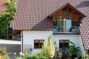 ein weißes Haus mit einem Holzdach und einem Balkon in der Unterkunft Ferienwohnung Keller in Hagnau