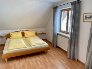 una camera da letto con un letto con cuscini gialli e una finestra di Ferienwohnung Keller a Hagnau