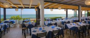 Ein Restaurant mit Tischen und Stühlen, im Hintergrund das Meer. in der Unterkunft Hotel Negretto in Caorle + 41 Fotos