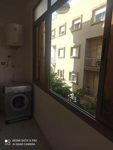 - un lave-linge dans une chambre avec fenêtre dans l'établissement شقة بإقامة الجوهرة الصويرة الصويرة, à Essaouira
