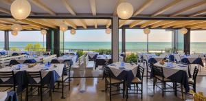 Ein Festsaal mit Tischen und Stühlen, im Hintergrund das Meer. in der Unterkunft Hotel Negretto in Caorle