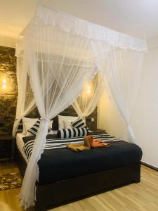 a bedroom with a canopy bed with white curtains at Sky Garden Ella in Ella