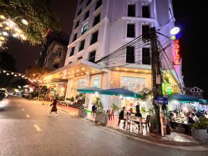 un grupo de personas sentadas fuera de un restaurante por la noche en 4M2 Hotel en Hòa Ðình