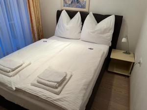 ein großes Bett mit weißer Bettwäsche und Handtüchern darauf in der Unterkunft Berghaus in Ellmau
