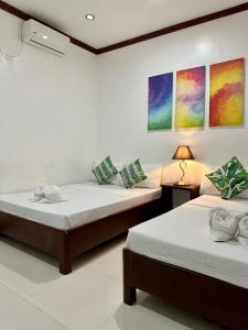 2 camas en una habitación con pinturas en la pared en Endless Summer Hotel Baler en Baler