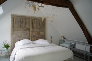 a bedroom with a white bed with a wooden door at Les Hirondelles in Baguer-Pican