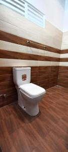 aseo blanco en un baño con paredes de madera en Airport Pearl Garden Transit Hotel, en Arambe