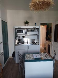 una pequeña cocina con mesa y encimera en Charmant studio 8, parking et wifi gratuit, arrêt navette, en Bagnoles de l'Orne