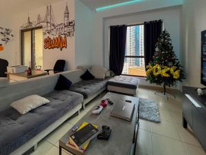 Silvana Deluxe Hostel في دبي: غرفة معيشة مع أريكة وشجرة عيد الميلاد