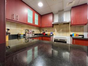 a kitchen with red cabinets and a white stove at Silvana Deluxe Hostel in Dubai