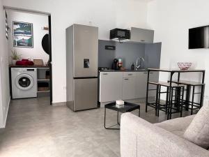 a kitchen and living room with a couch and a table at Appartement «Le Ti songe» in Saint-Joseph