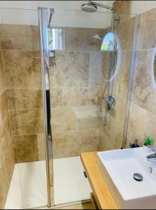 a shower with a glass door next to a sink at Le petit Chapitre in Pinterville +30 photos