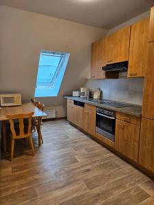 eine Küche mit Holzschränken, einem Tisch und einem Fenster in der Unterkunft 3 Zimmerwohnung am Neuer Teich in Wolfsburg