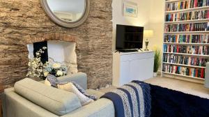 a living room with a stone wall with a couch and a mirror at Dartmouth Town Centre nautical stylish apartment is perfect for couples with a happy and homely feel being only 30 meters from the sea but set back and quiet with everything on your doorstep a gorgeous place to explore the Devon beaches 5 star feedback in Dartmouth