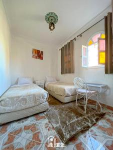 a bedroom with two beds and a table and a window at Hotel Dar Youssef 1 in Marrakesh