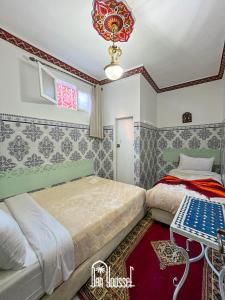 Hotel Dar Youssef 1 في مراكش: غرفة نوم بسريرين وطاولة فيها