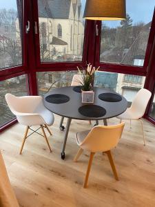 einen Tisch und Stühle in einem Zimmer mit Fenstern in der Unterkunft Stilvolle helle Wohnung im Zentrum in Osnabrück