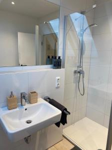 y baño blanco con lavabo y ducha. en Stilvolle helle Wohnung im Zentrum, en Osnabrück