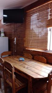 una mesa de madera en una habitación con TV en la parte superior en Cabañas azules, en Punta del Diablo