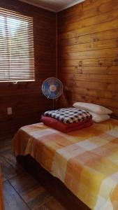 a bedroom with a bed with a fan on it at Cabañas azules in Punta Del Diablo