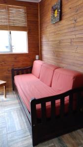 Bett in einem Zimmer mit einer Holzwand in der Unterkunft Cabañas azules in Punta Del Diablo