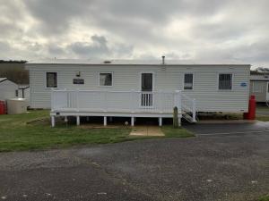 a white mobile home with a porch in a parking lot at Weymouth Bay Haven, Preston Road in Weymouth