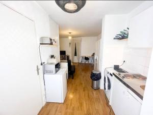 eine Küche und ein Wohnzimmer mit weißen Wänden und Holzböden in der Unterkunft Studio à 5min du Stade de France (JO 2024) in Villeneuve-la-Garenne