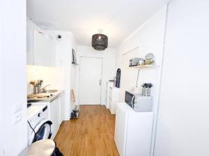 eine weiße Küche mit einer Spüle und einer Mikrowelle in der Unterkunft Studio à 5min du Stade de France (JO 2024) in Villeneuve-la-Garenne