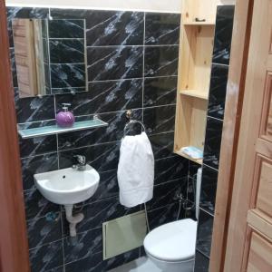 a black tiled bathroom with a toilet and a sink at Villa Paradis in Marrakech