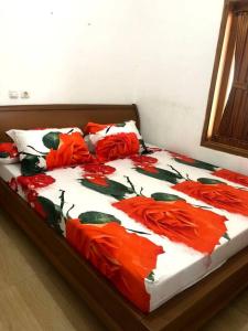 un letto con fiori rossi sopra in una camera da letto di Villa Sari Leueut Suramadu Majalengka 