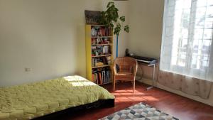 ein Schlafzimmer mit einem Bett, einem Schreibtisch und einem Bücherregal in der Unterkunft Maison des Peupliers in Bondy