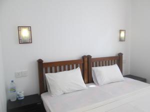 łóżko z 2 białymi poduszkami w pokoju w obiekcie Bay Reach Home Stay w mieście Weligama