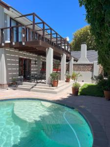 a swimming pool in front of a house at Pinoak Self Catering Cottages - Constantia in Cape Town