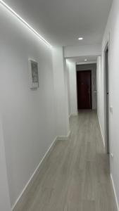 Apartamento Arena Benidorm في بنيدورم: ممر فارغ بجدران بيضاء وارضيات خشبية