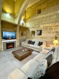 un grand salon avec un mur en pierre dans l'établissement Daner Ta’ Pantu House, à Kerċem