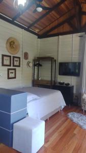 een slaapkamer met een wit bed en een televisie bij Espaço Isha in Canelinha
