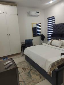 een slaapkamer met een groot bed, een bureau en een stoel bij Hi Apartments in Lagos