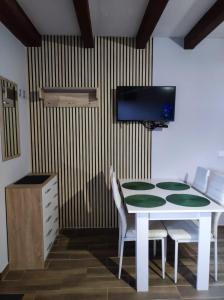 ein Esstisch mit Stühlen und einem Fernseher an der Wand in der Unterkunft Domki w Bieszczadach Nova Dolina in Średnia Wieś