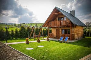 ein Blockhaus mit einem Spielplatz und zwei blauen Stühlen in der Unterkunft Domki w Bieszczadach Nova Dolina in Średnia Wieś + 8 Fotos